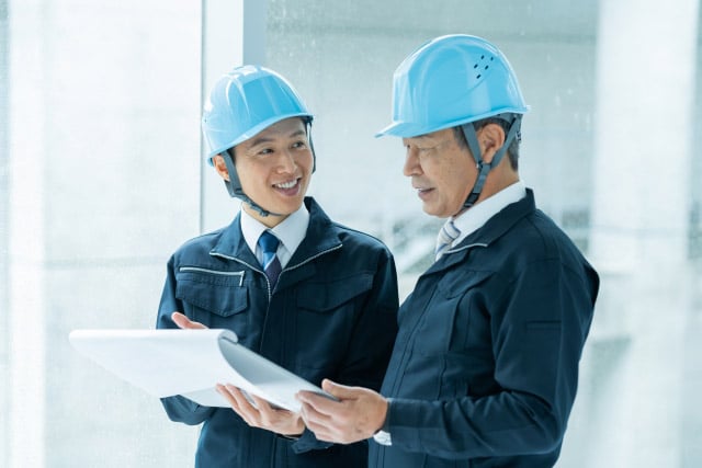 建設現場で資料をみて打ち合わせをする男性